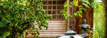 Wooden structure in a garden with foliage and metal statues.