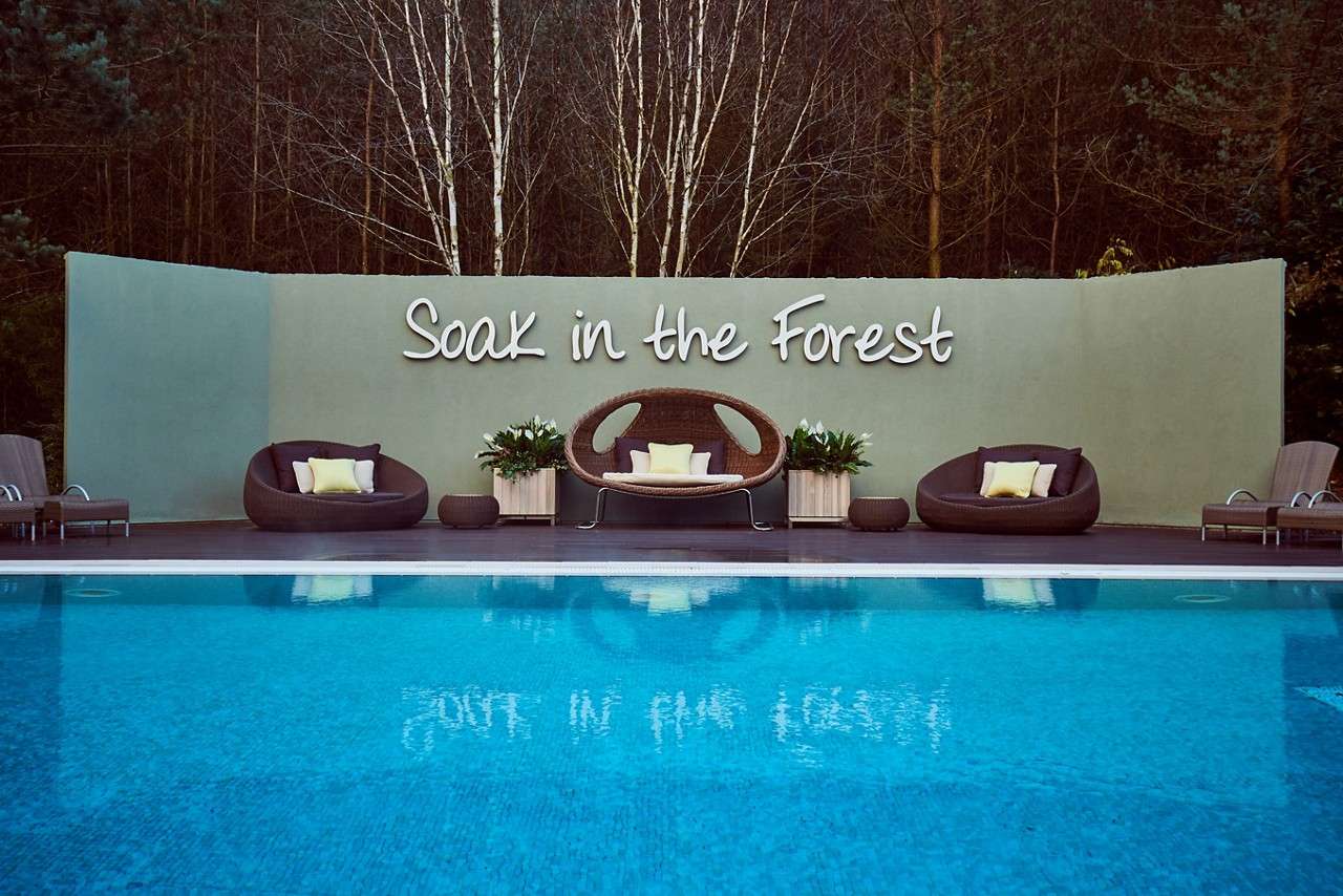 Wooden decking with comfortable seating by an Outdoor Pool in the forest.