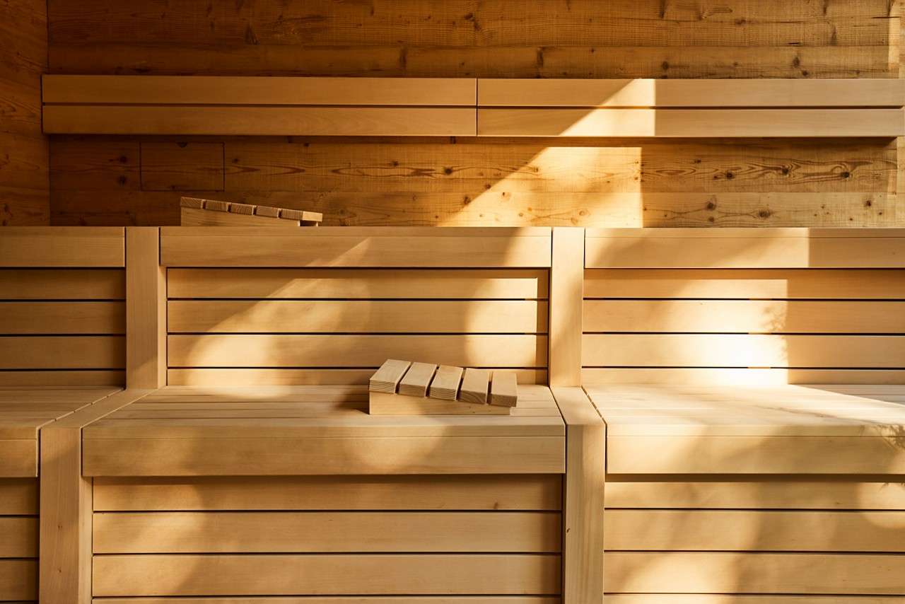 The sun shining in on a wooden sauna with tiered seating.