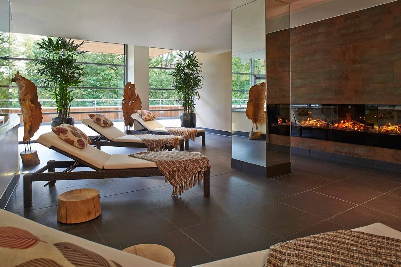 Large relaxation space with natural lighting, comfortable lounging beds and an open fire.