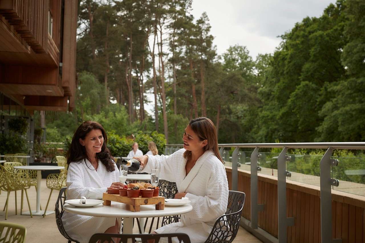 Two women eating on a terrace in the forest.