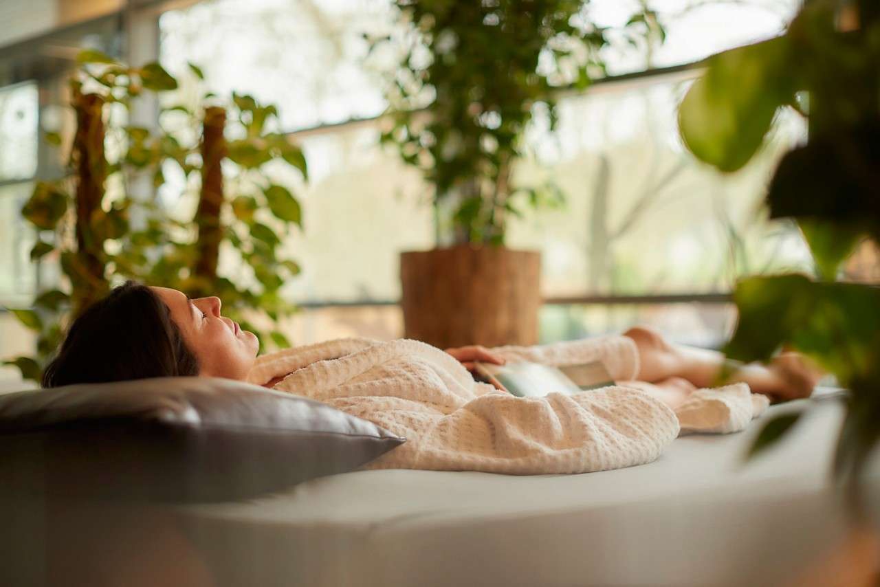 Woman laid on a waterbed surrounded by plants
