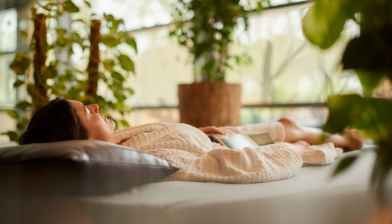 Woman laid on a waterbed surrounded by plants