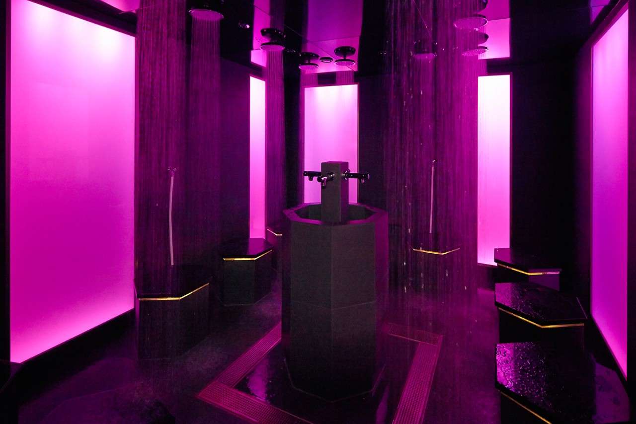 Mineral steam room with tall pillars bathed in purple light.