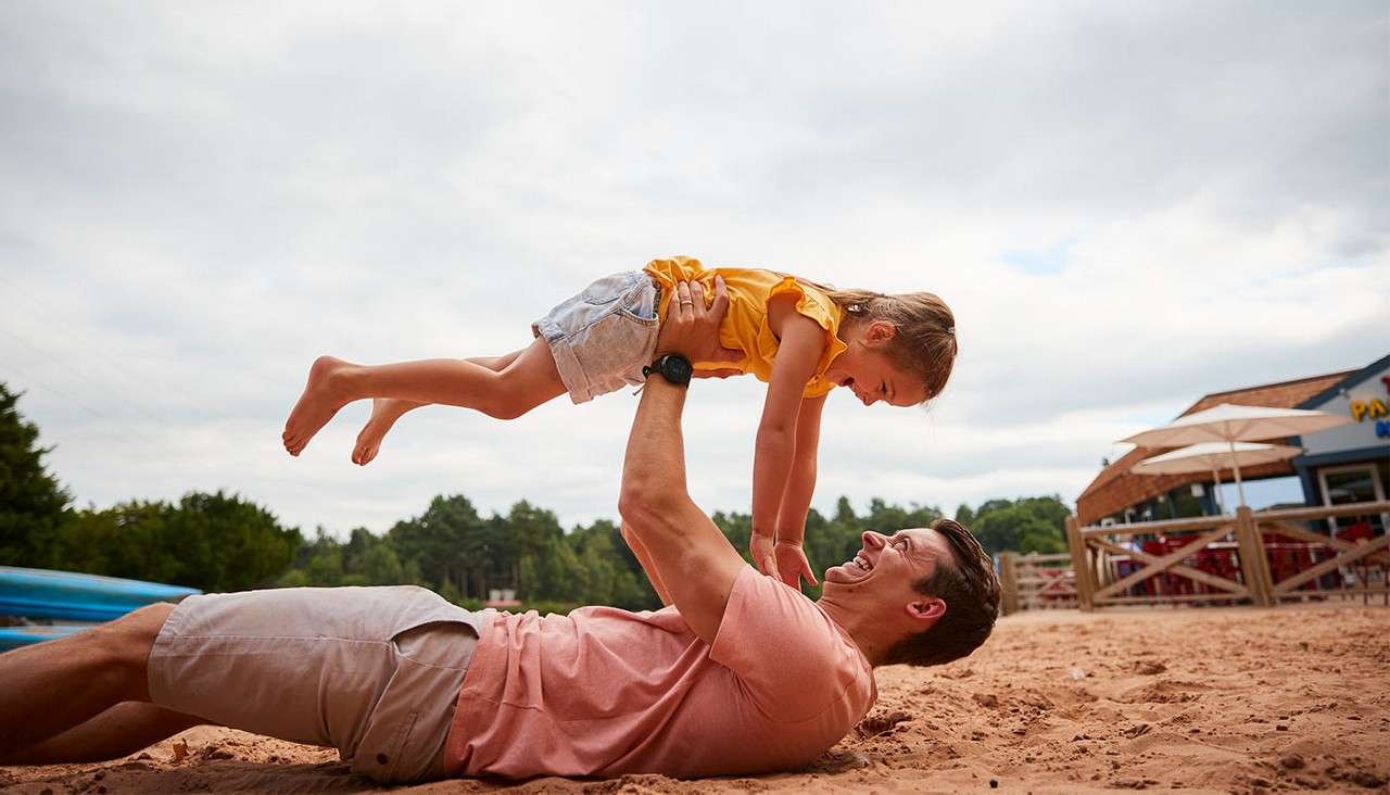 A father on the beach with his daughter.