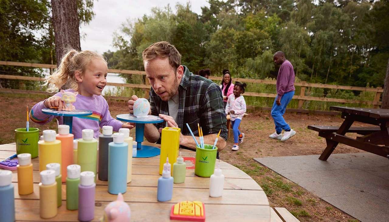A father and daughter paiting pottery together. 