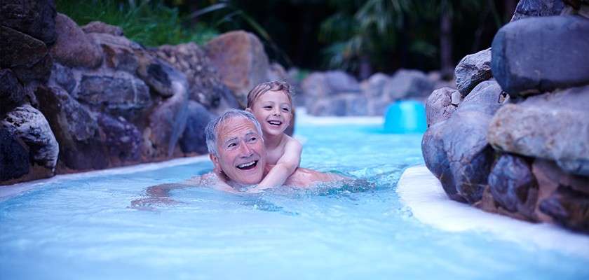 A grandfather carrying his grandson on piggyback through the rapids of the Subtropical Swimming Paradise.