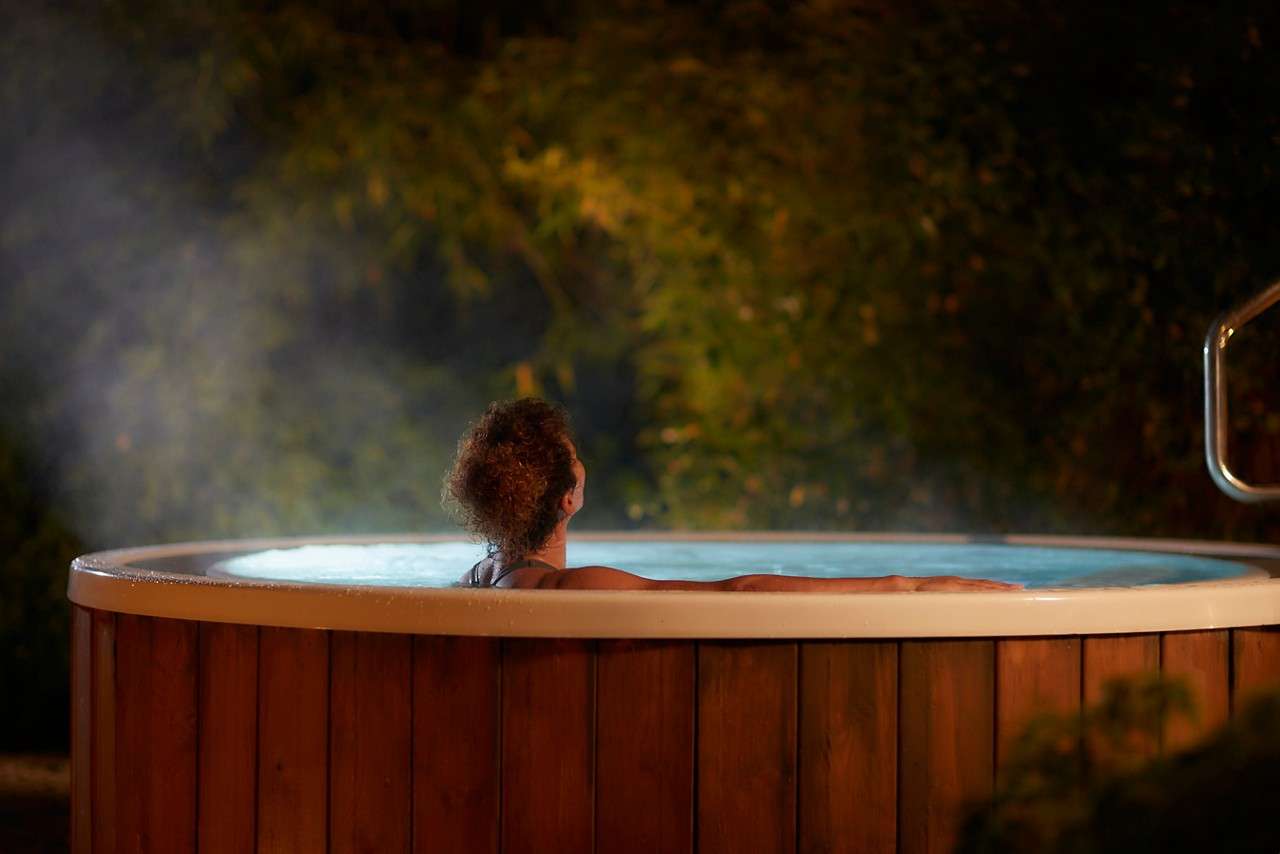 Woman soaking in a bubbling outdoor hot tub.