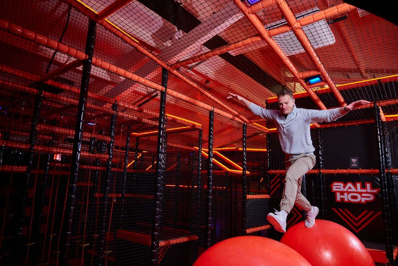 A man climbing across giant red balls in the arena.
