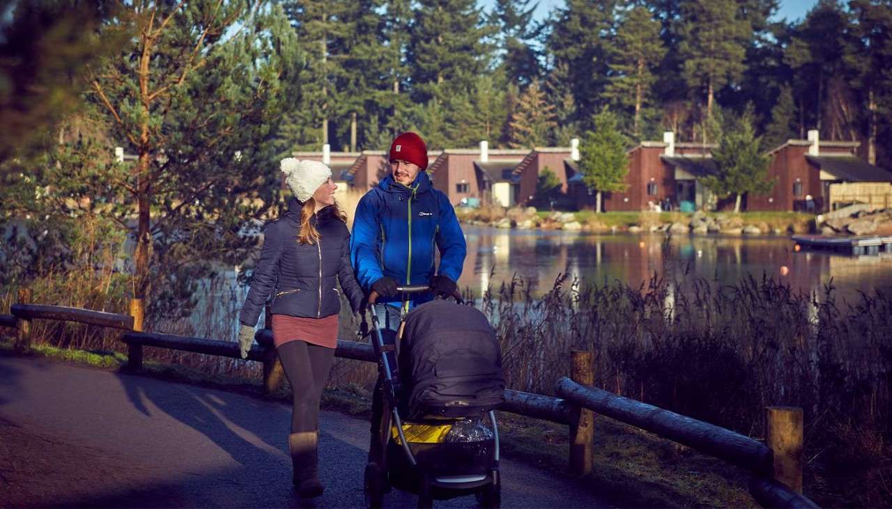 A couple walking with a pram by the lake