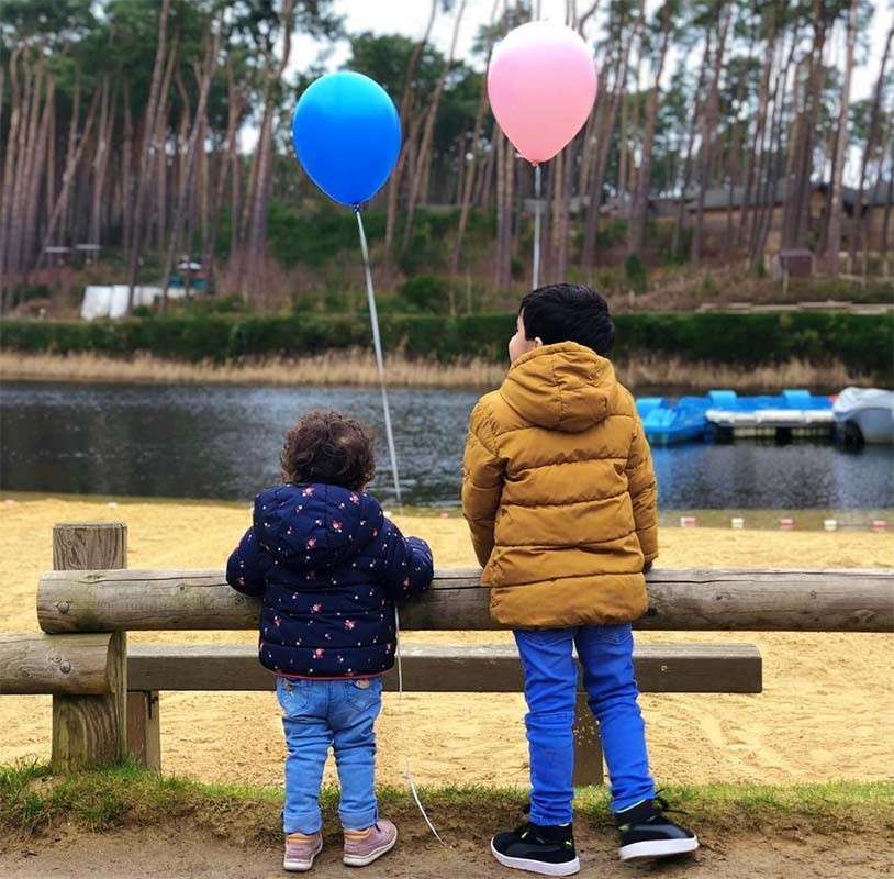 Two children with balloons next to the beach
