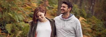 A man and pregnant woman on a relaxing walk through the forest.