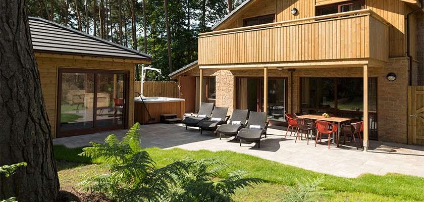 External view of an adapted lodge with hot tub and sun loungers.
