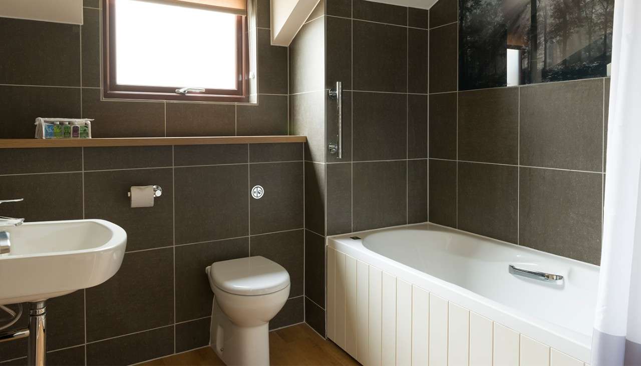 A bathtub, toilet, sink, and mirror in an Exclusive Lodge bathroom 