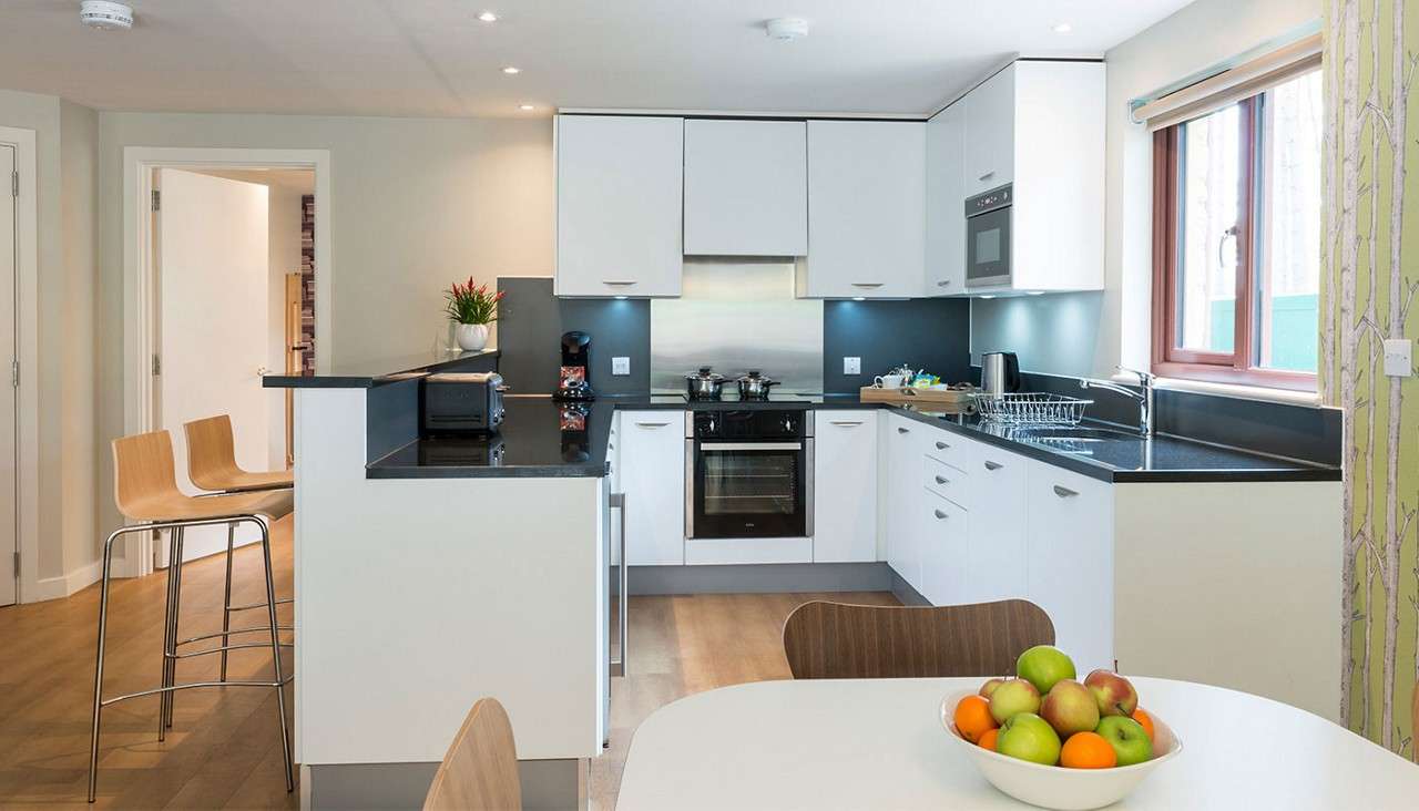 The kitchen in an Exclusive Lodge with an oven, a hob, plenty of storage space and a bar-style counter with tall chairs