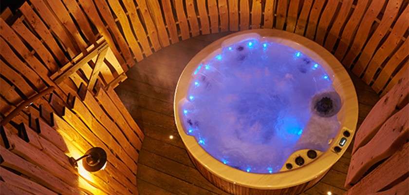An aerial shot of a bubbling hot tub lit up with blue lights at night time.