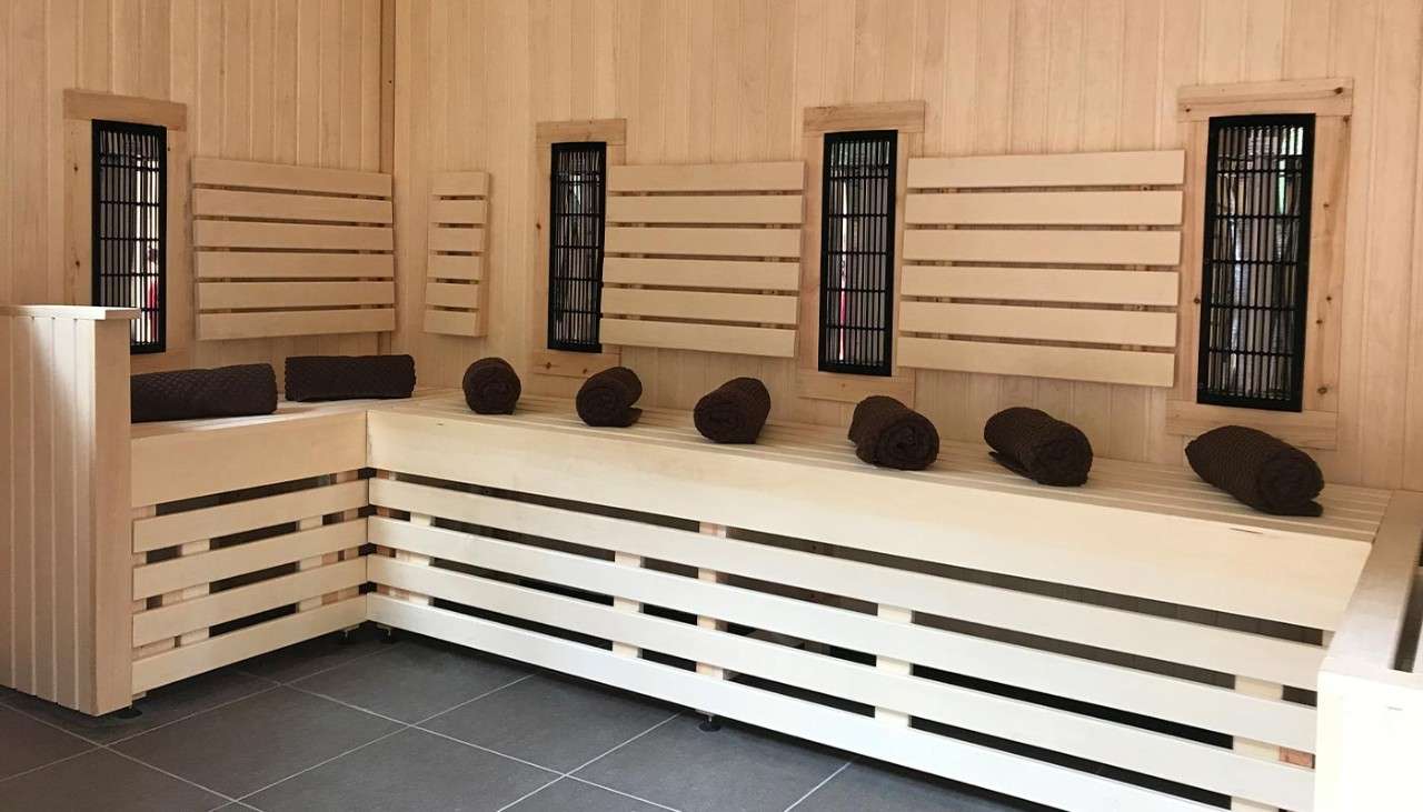 The inside of an infrared sauna with towels on the seating area. 