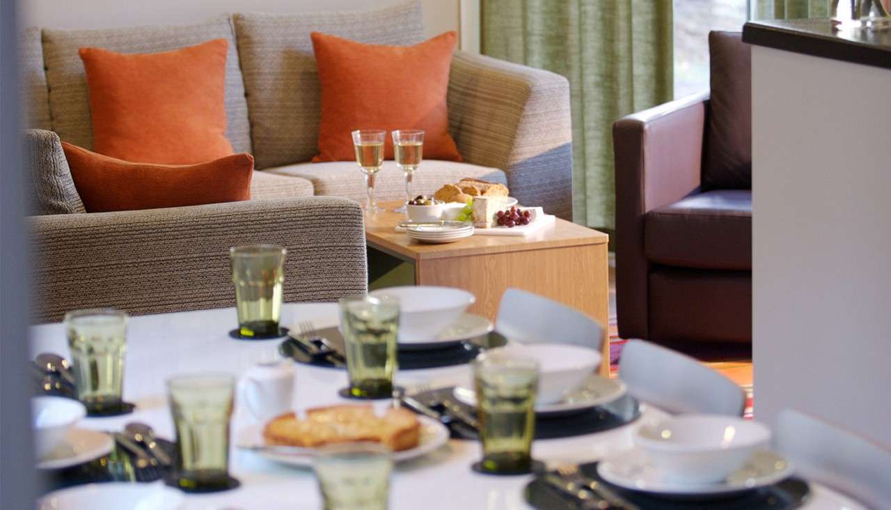 A neatly laid dining table and sofa in a Woodland Lodge