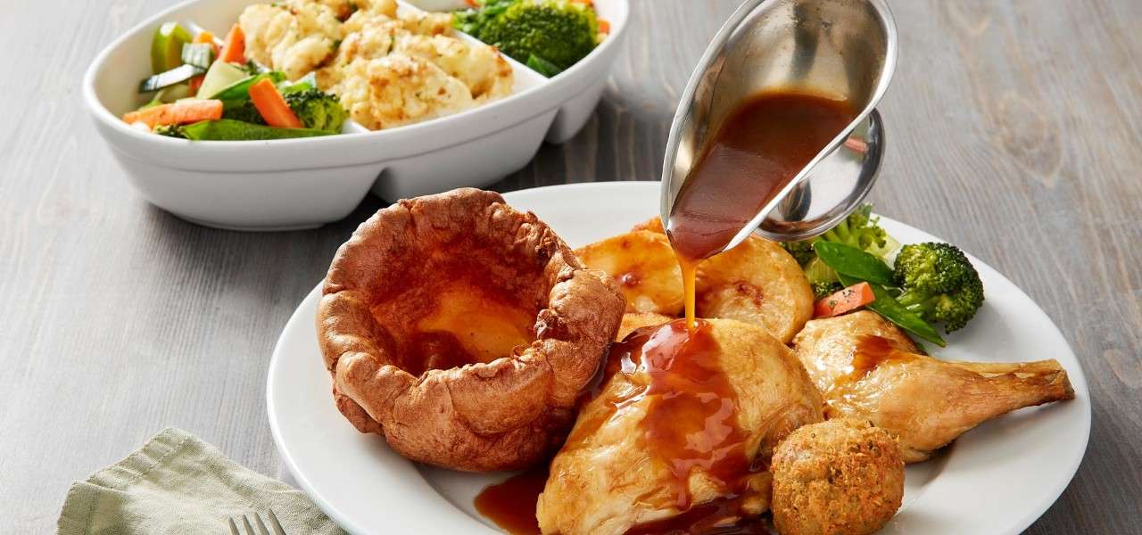Roast chicken served with seasonal vegetables, a Yorkshire pudding and gravy