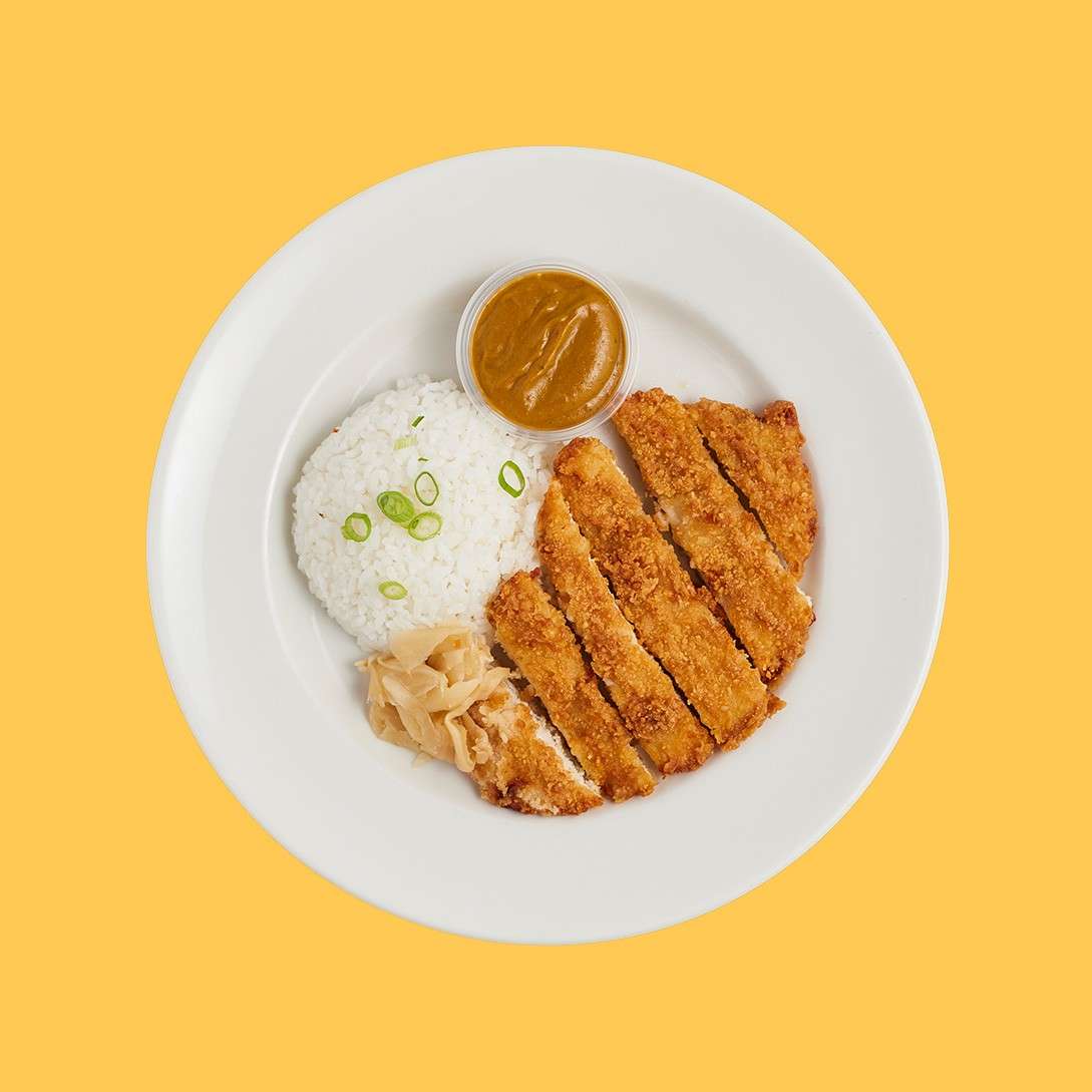 Strips of panko chicken served with white rice, Japanese pickles and a pot of Katsu sauce.