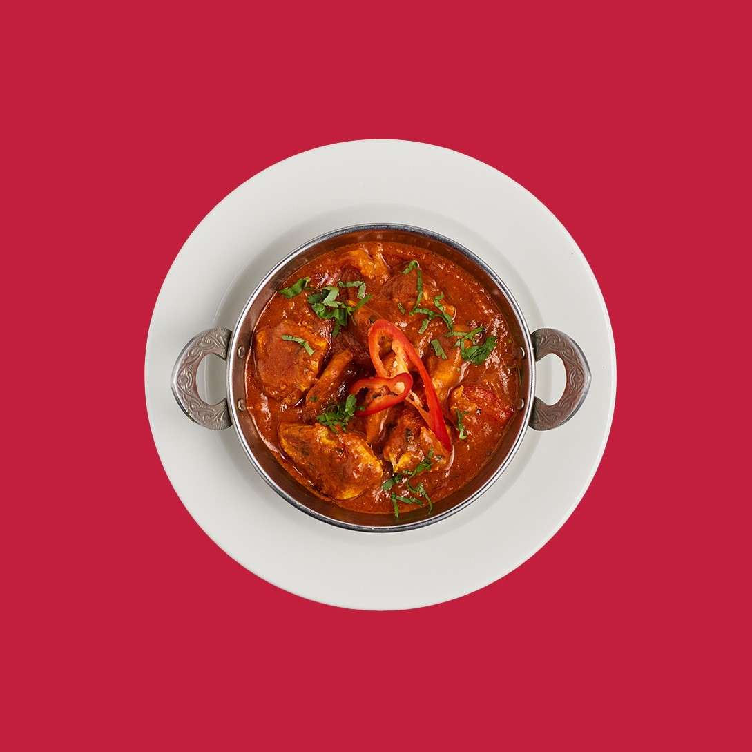Chicken chilli balti served with sliced chilli in a traditional bowl.