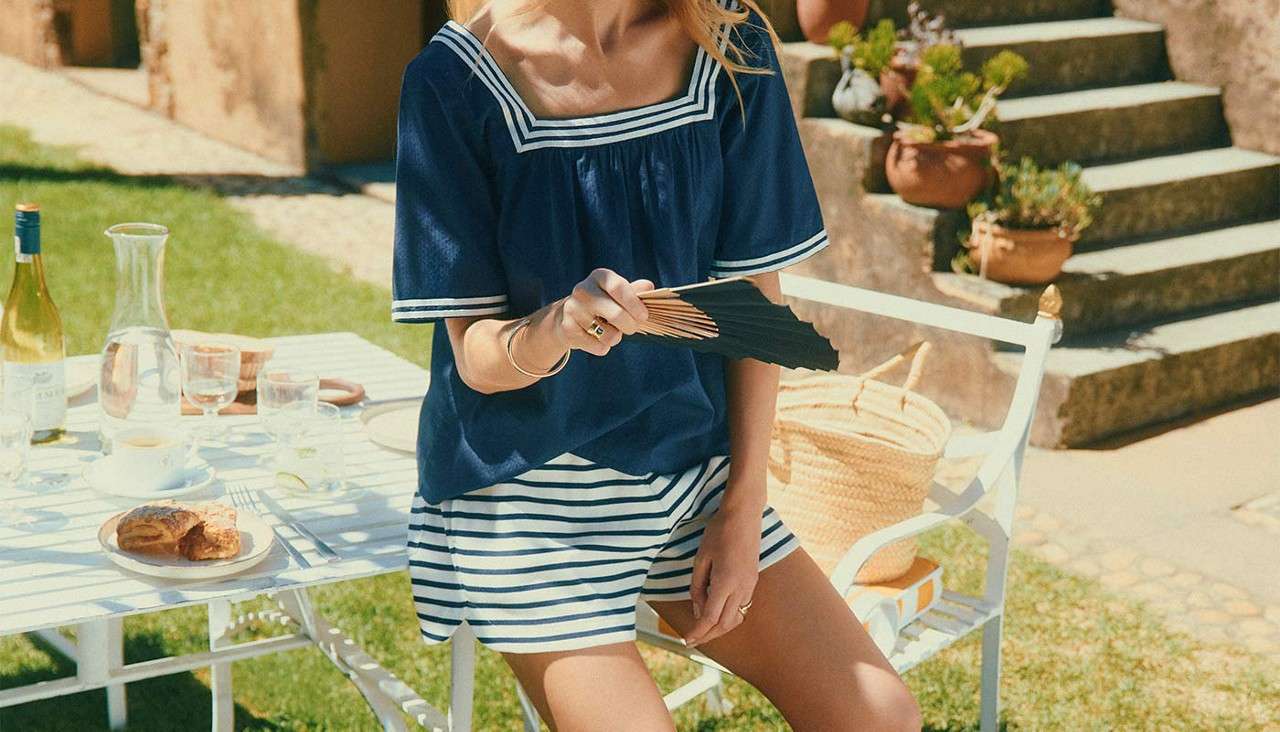 Woman in stripy shorts and a navy blouse.