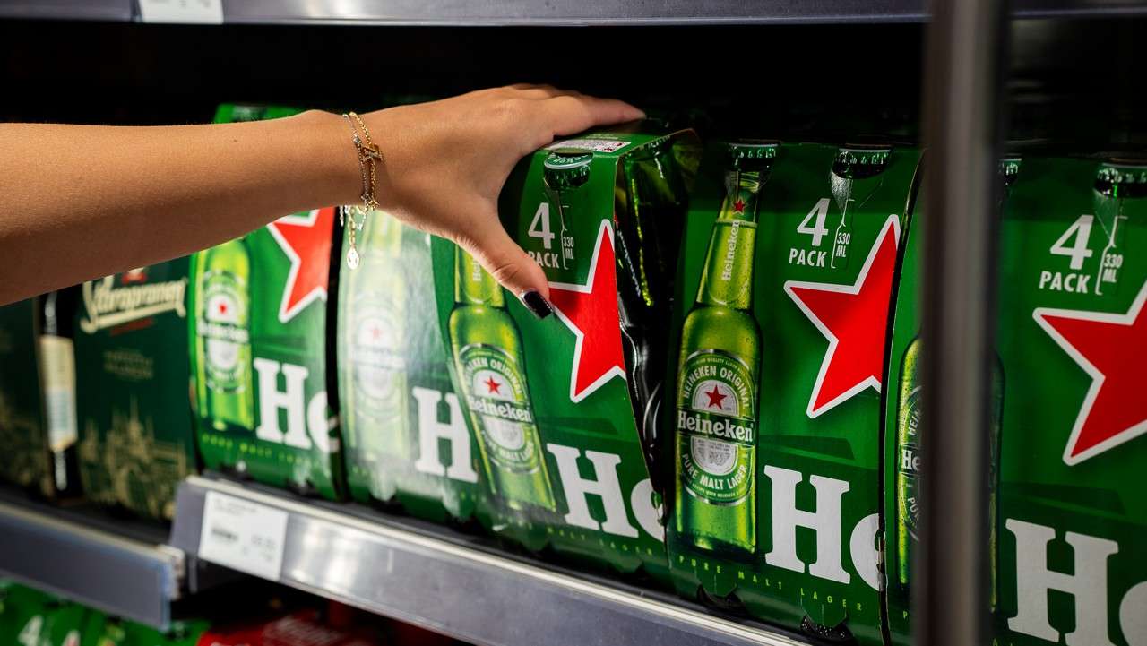 a hand picking up a packet on Heineken