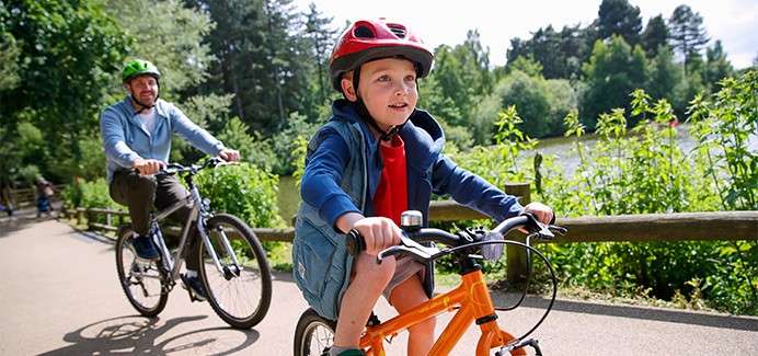 A father and his toddler cycling past the lake.