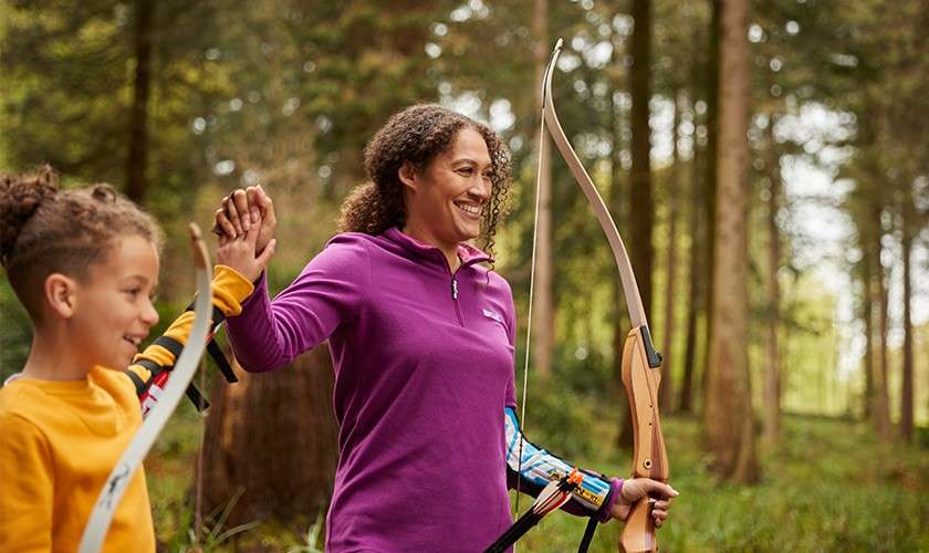 Sister and brother giving each other a high five whilst doing Archery.