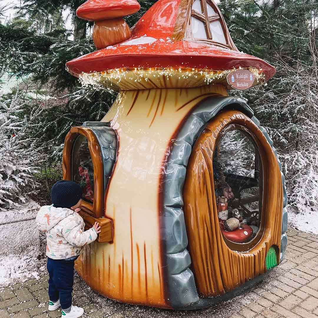 A boy looking inside toadstool home in Santa's Woodland Village.