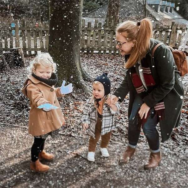 A mother and her two young children play in the snow