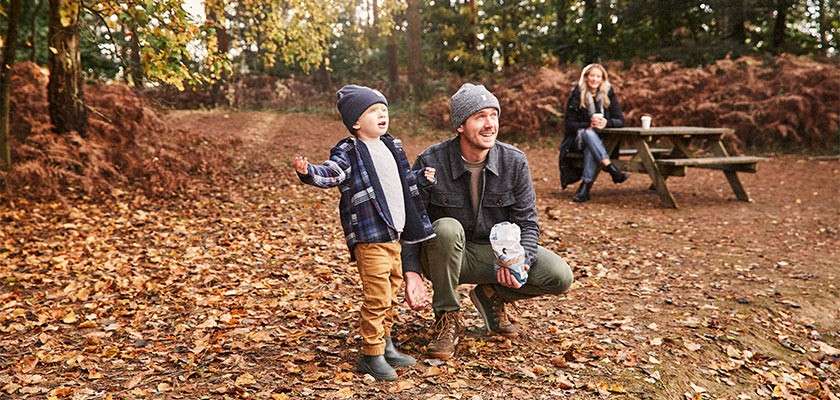A father and son playing amongst the autumnal leaves.