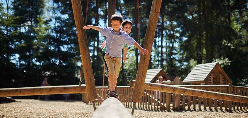 Boys playing on a wooden climbing frame.