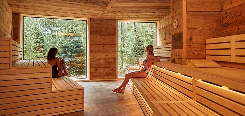 Two women relaxing in a wooden Nordic sauna.