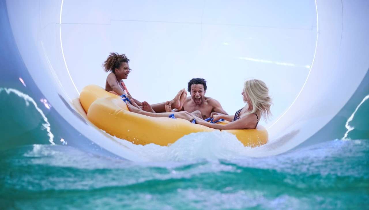 Three young adults sliding down the Tropical Cyclone water slide.