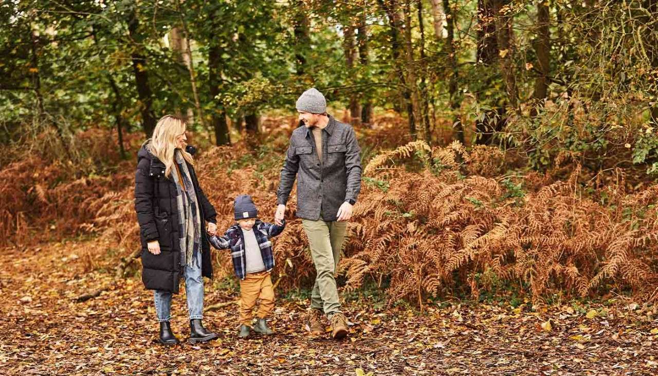 A family holding hands and walking through the autumnal forest.