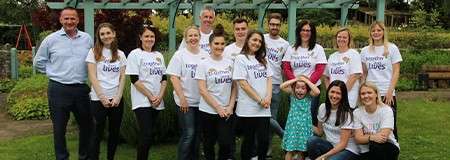 A group of adults wearing 'Together for short lives' shirts smiling at the camera.