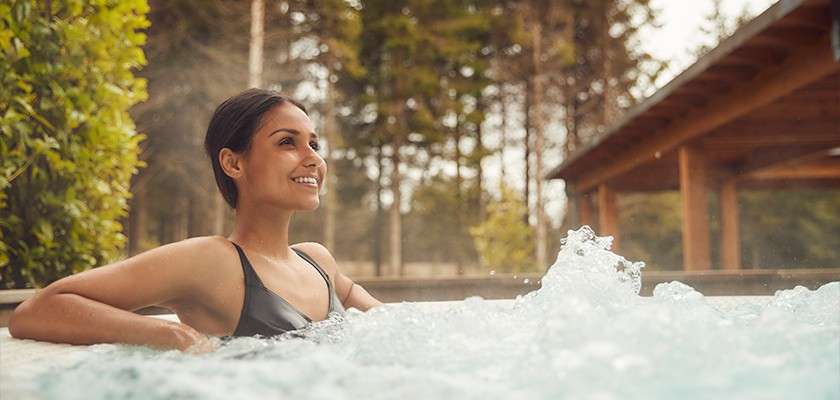 A woman relaxing in an outdoor hot tub.