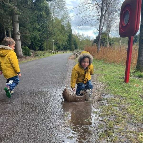 A child jumping in a muddy puddle