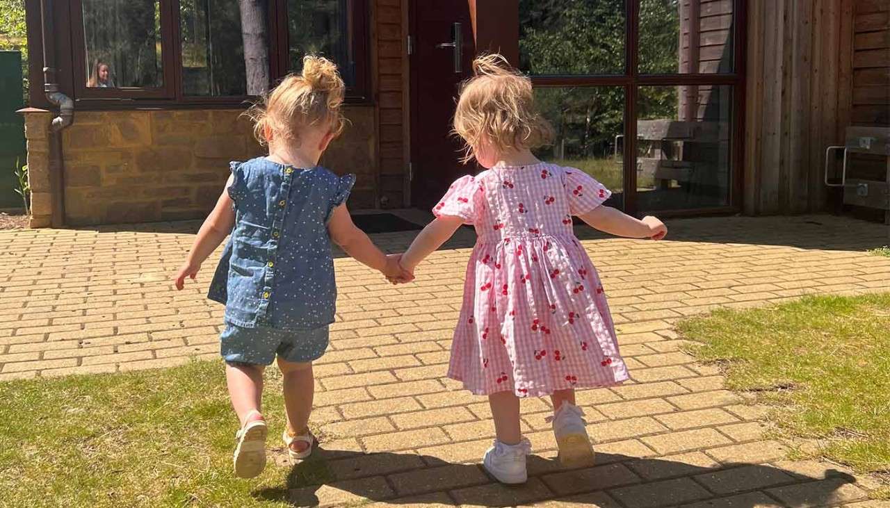 Two small toddlers holding hands on the entrance to their Treehouse.