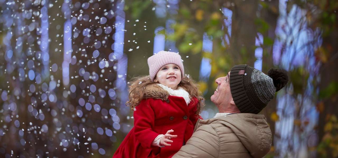 Father holding his daughter looking up at the snow.