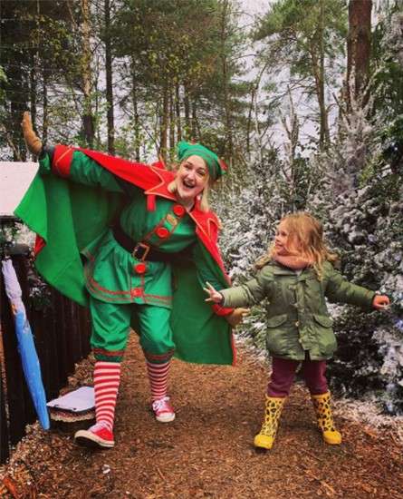 A young girl poses with one of Santa's elves
