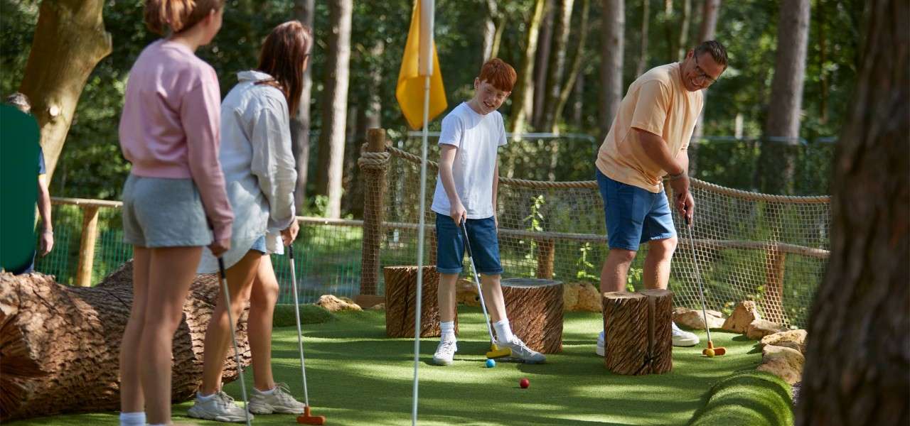 Family standing playing Adventure Golf 