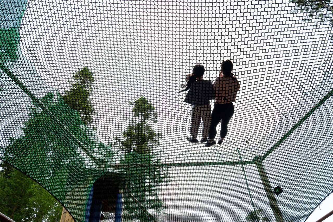 Two people laid on a suspended net course.