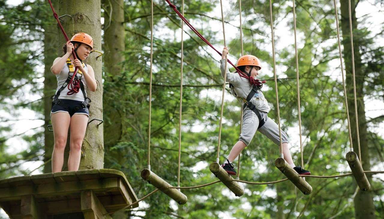 Two young people crossing a suspended bridge 