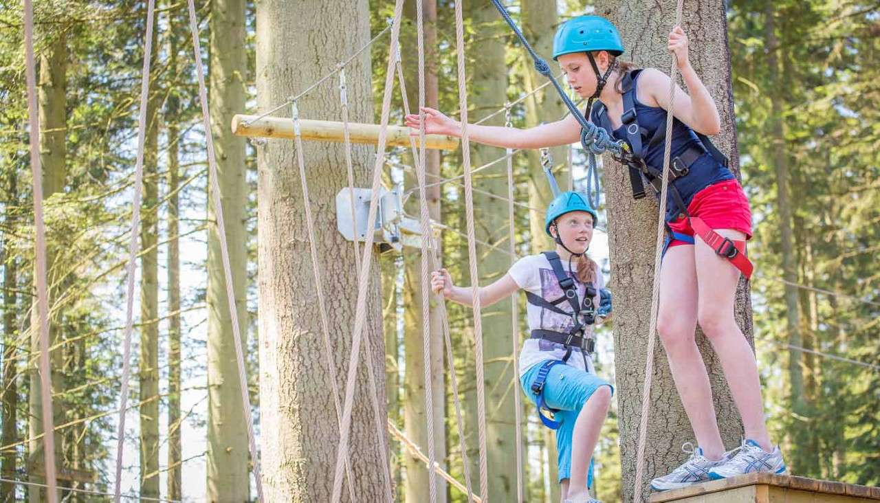 Two young people crossing a suspended bridge