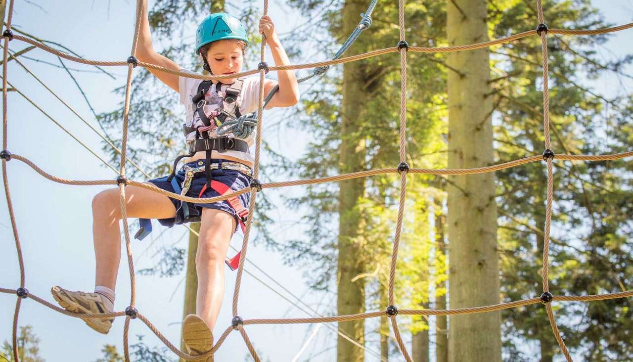 A young person walking a suspended rope bridge