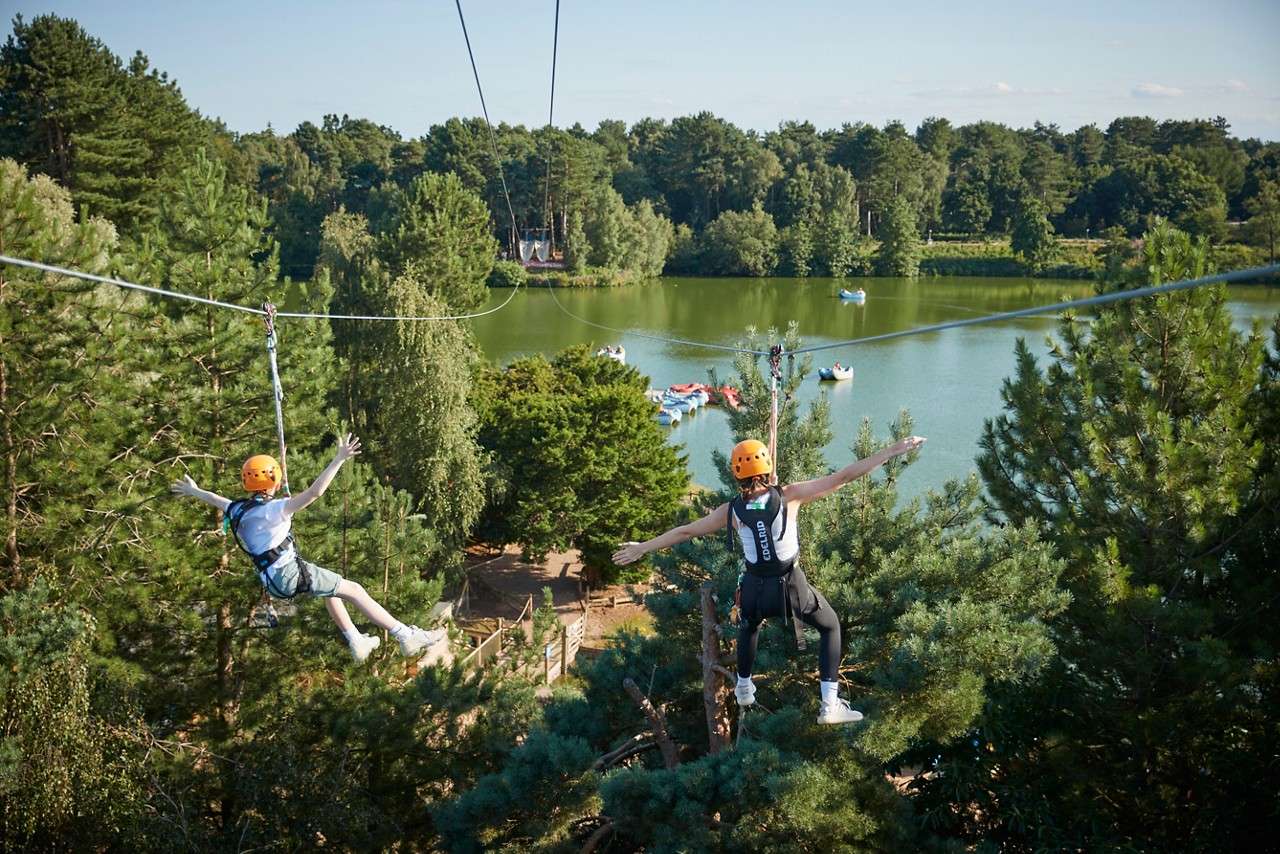 Two people zip lining over the lake.