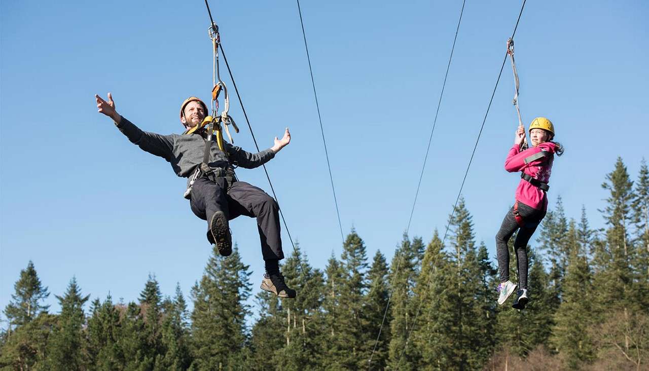 Two people coming down zip wire