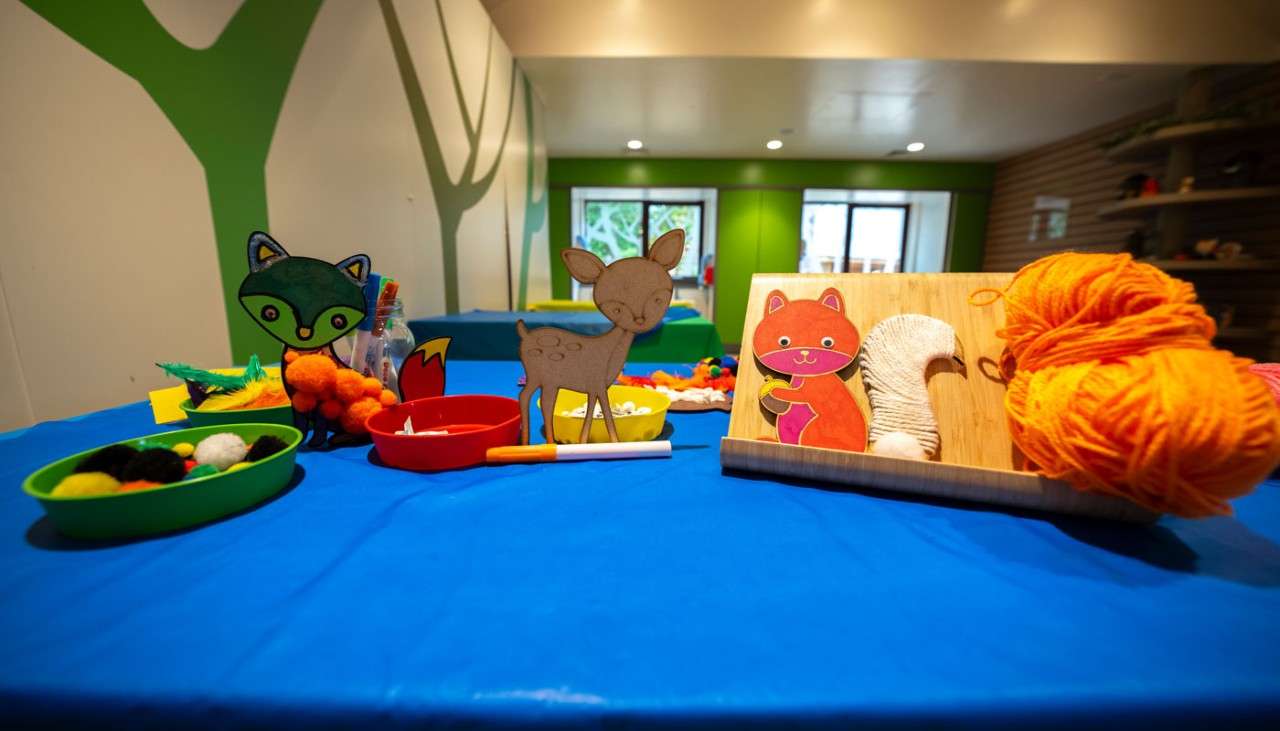 Mini wooden deer and squirrel surrounded by colourful craft materials.